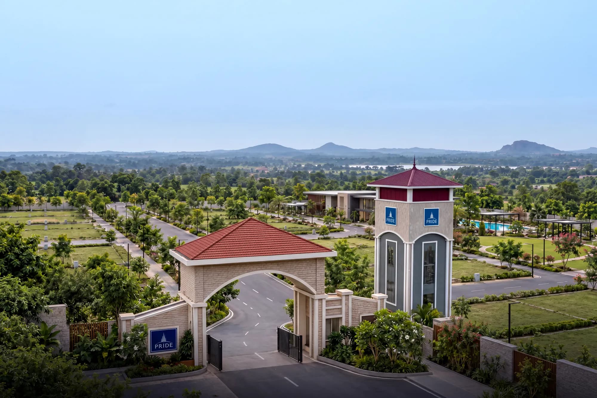 The entrance arch and clock tower, with the plotted layout and clubhouse beyond